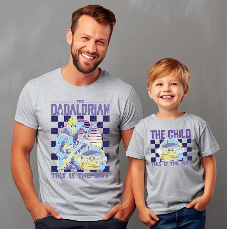 A man and a young boy wearing matching t-shirts with a graphic design featuring a character from the Star Wars franchise.