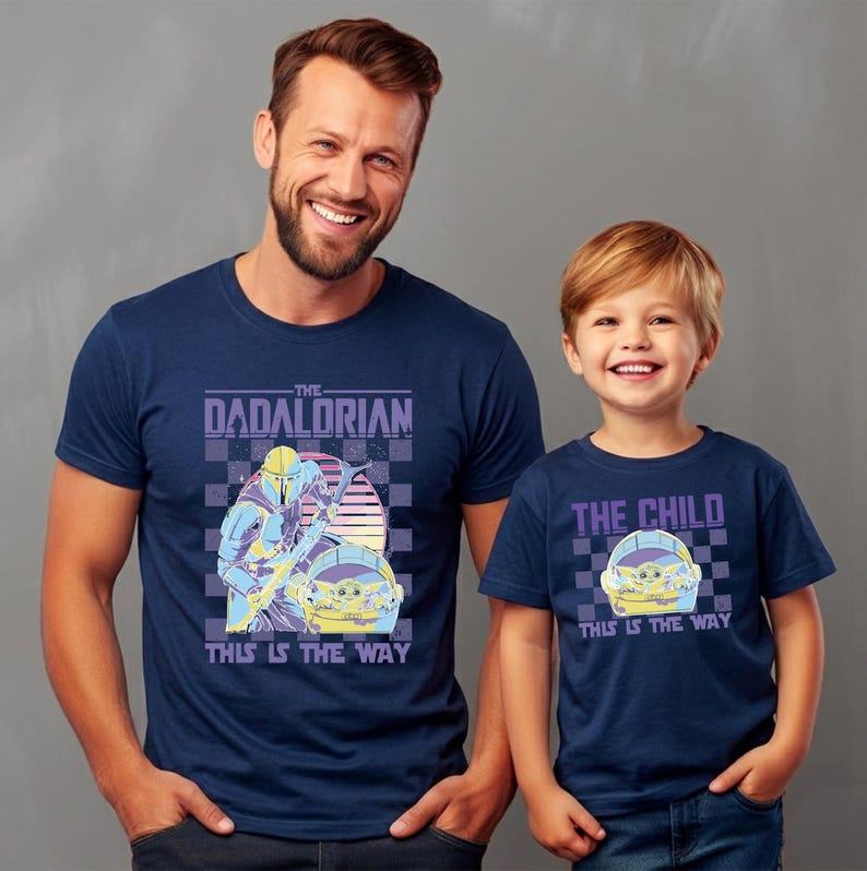 A man and a young boy wearing matching blue t-shirts with a graphic design.