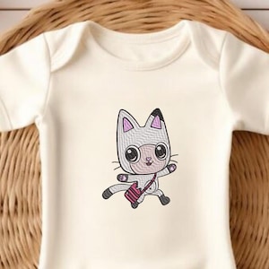 Peut inclure: Combinaison blanche pour bébé avec un chat de dessin animé portant un sac rayé rose et blanc. Le chat est gris avec des oreilles roses et des yeux noirs.