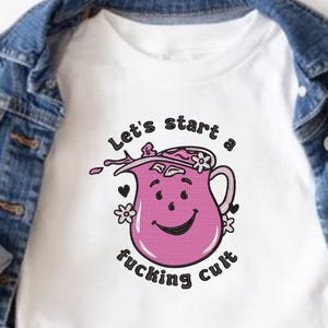 May include: White t-shirt with a pink pitcher graphic. The pitcher has a smiling face and is decorated with flowers. The text "Let's start a fucking cult" is above and below the pitcher.