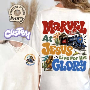 May include: White t-shirt with a retro-style graphic design featuring a train, cactus, and the text "Marvel at Jesus Live For His Glory".