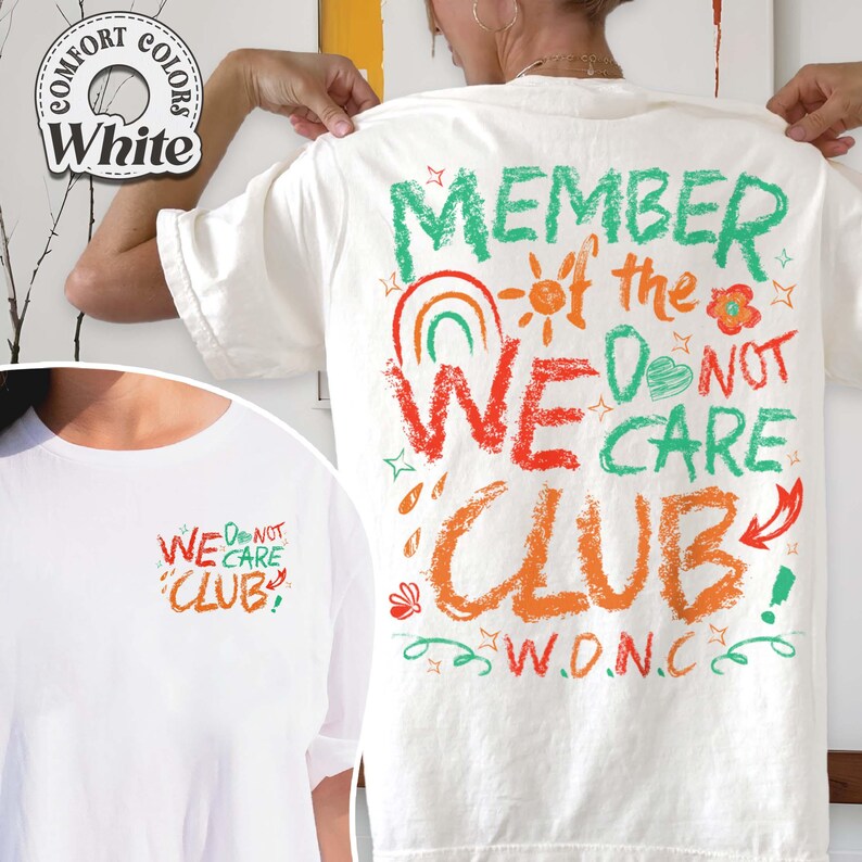 May include: White t-shirt with the text "MEMBER of the WE DO NOT CARE CLUB" in green, orange, and red. The design includes a rainbow, sun, flower, and stars. The shirt also has the text "W.D.N.C."