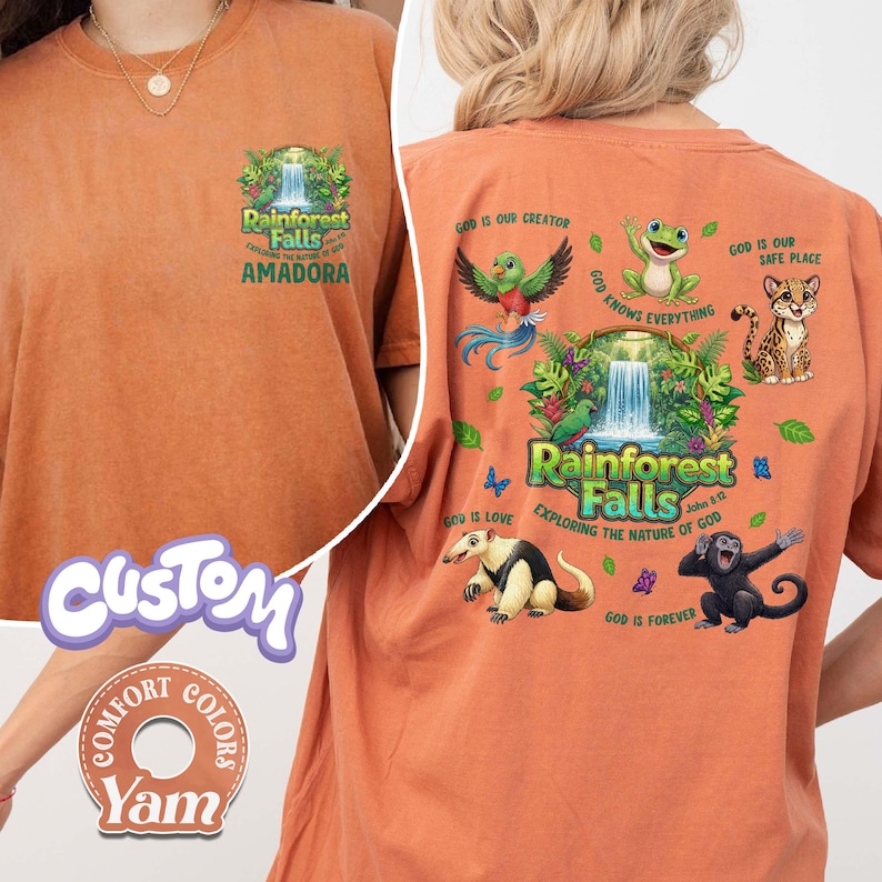 May include: Orange t-shirt with a rainforest graphic on the front and back. The front features text that reads "Rainforest Falls Amadora". The back has a waterfall scene with various animals and text that reads "Rainforest Falls Exploring the Nature of God".