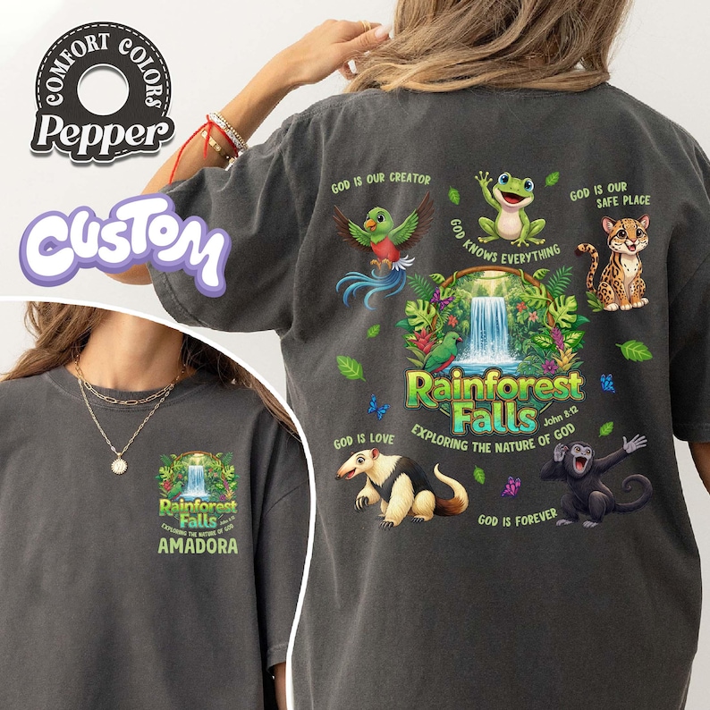 May include: Dark grey t-shirt with a vibrant rainforest design, including the text "Rainforest Falls" and illustrations of animals. The shirt also features the text "Exploring the Nature of God" and "Amadora".