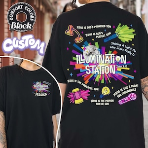 May include: Black t-shirt with a colorful graphic design. The design includes the words "ILLUMINATION STATION" and various religious phrases and illustrations. The shirt also features the text "John 8:12".