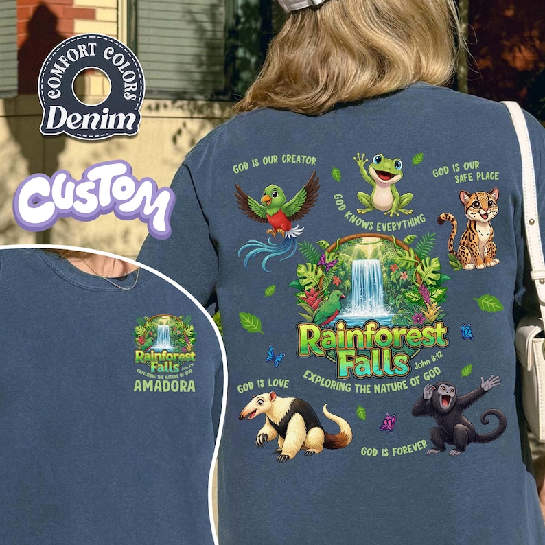May include: Denim blue long-sleeve shirt with a colourful rainforest graphic. The design includes a waterfall, various animals, and the text "Rainforest Falls" and "Exploring the Nature of God". The shirt also features the text "Amadora".