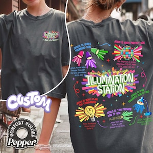 May include: Dark gray t-shirt with the text "ILLUMINATION STATION" and colorful graphics. The back of the shirt features religious text and illustrations, including a disco ball and a lightbulb.