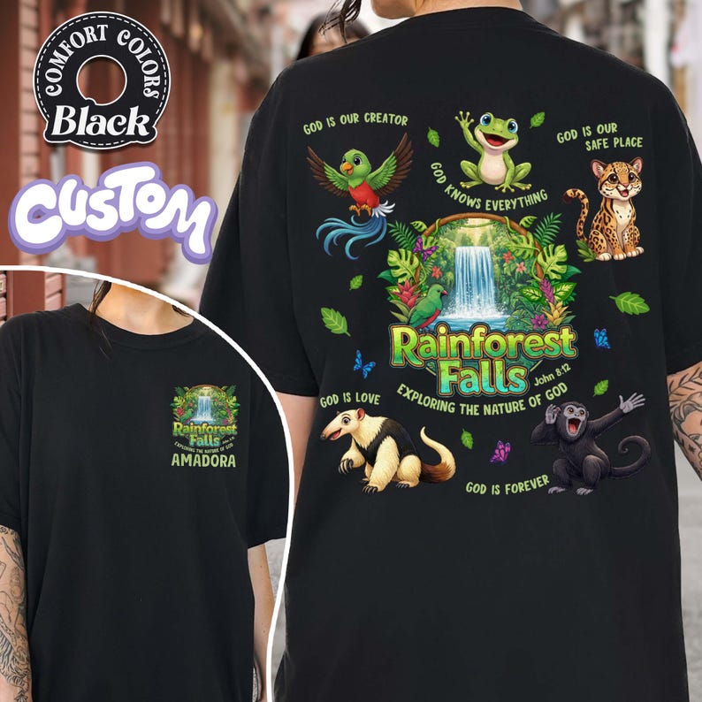 May include: Black t-shirt featuring a vibrant rainforest design with a waterfall, animals, and the text "Rainforest Falls" and "Exploring the Nature of God". The shirt also displays the phrases "God is our Creator" and "God is our Safe Place".