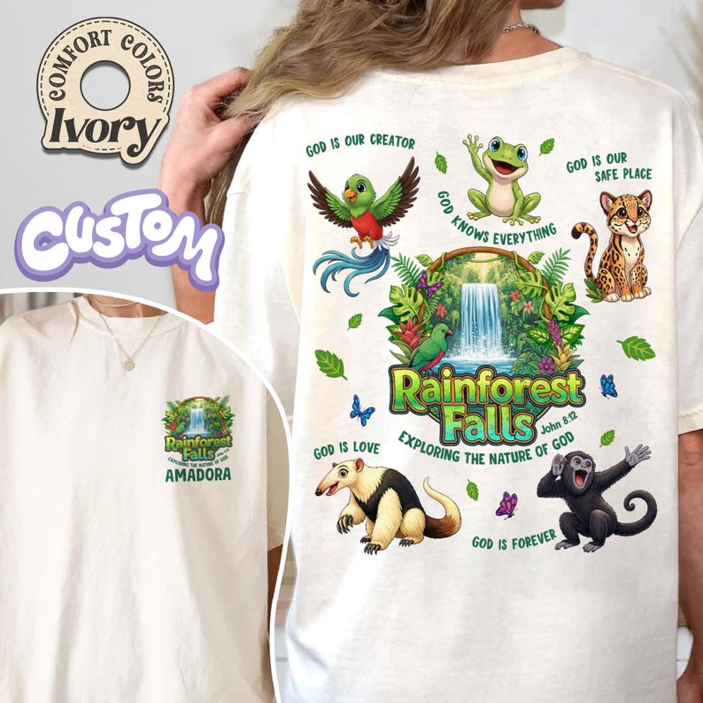 May include: Ivory t-shirt featuring a rainforest-themed design with a waterfall, animals, and the text "Rainforest Falls" and "Exploring the Nature of God". The design also includes the phrases "God is our Creator" and "God is Love".