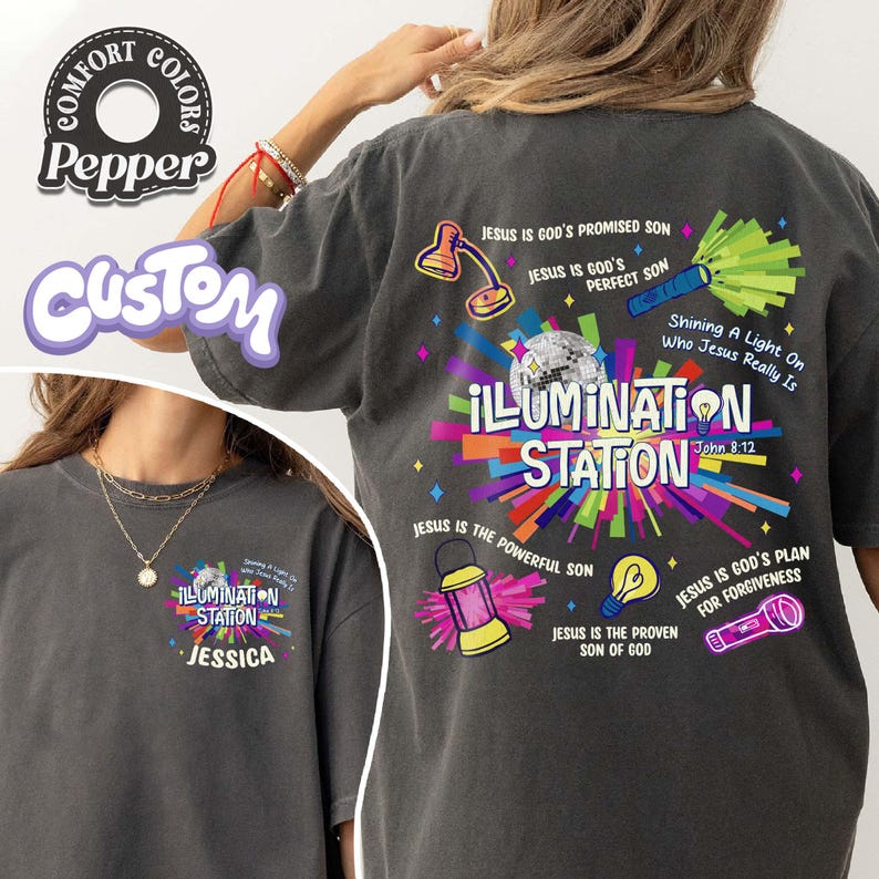 May include: Dark gray t-shirt with the text "ILLUMINATION STATION" and various graphic elements, including a disco ball, a lamp, and a flashlight. The shirt also features the name "JESSICA" and the phrase "Shining A Light On Who Jesus Really Is."