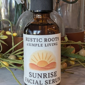 Puede incluir: Una botella de vidrio marrón con un tapón cuentagotas negro. La etiqueta dice "RUSTIC ROOTS & SIMPLE LIVING" y "SUNRISE FACIAL SERUM" con un gráfico de amanecer. La botella contiene un líquido oscuro.