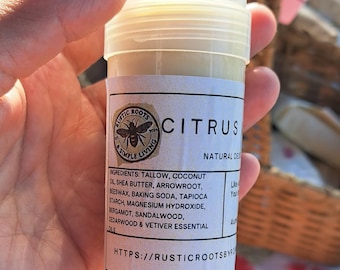 May include: A cylindrical natural deodorant stick with a white label featuring the text "CITRUS" and a bee logo. The ingredients are listed below. The deodorant is held in a person's hand.