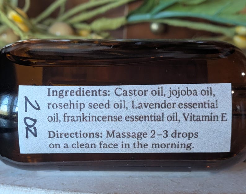 Puede incluir: Una botella de vidrio marr&oacute;n con una etiqueta blanca que muestra los ingredientes y las instrucciones de uso. La etiqueta enumera aceite de ricino, aceite de jojoba, aceite de semilla de rosa mosqueta, aceite esencial de lavanda, aceite esencial de incienso y vitamina E. La botella es de 59 ml.