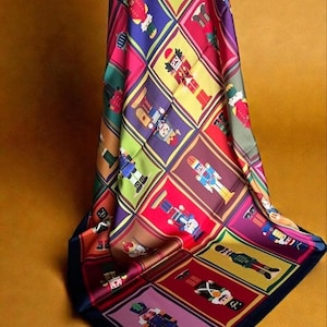 Bufanda de seda Cascanueces, con estampado de azulejos magenta y dorado, inspirada en la tradición navideña alemana.