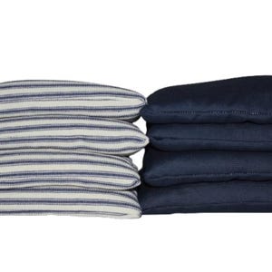 May include: A set of eight bean bags, four with a blue and white striped pattern and four solid navy blue. These bags are likely for a game like cornhole, with a simple, clean design.