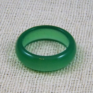 May include: A green jade ring with a smooth, polished finish. The ring is thick and has a rounded shape.