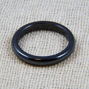 May include: A simple black ring made of polished hematite.