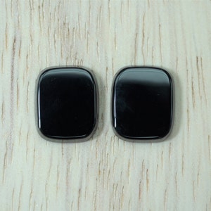 May include: Two black square-shaped cabochon gemstones.