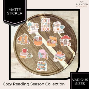 May include: A collection of matte stickers featuring autumn-themed reading illustrations, including a pumpkin bookshelf, a mushroom house, a stack of books with an apple, a cozy armchair, and text reading Cozy Up With A Good Book and Reading Season.