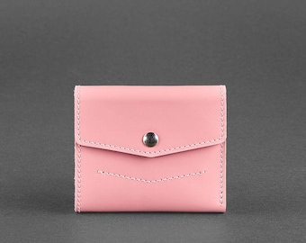 May include: A small, pink leather wallet with a snap closure. The wallet has a flap that folds over and is secured with a silver-colored snap. White stitching accents the edges and the front of the wallet.