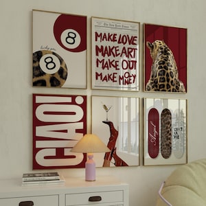 May include: A collection of framed art prints with gold frames. The prints feature various designs, including an 8-ball with leopard print, text from The New York Times, a leopard, the word "CIAO!", a martini, and skateboards with text and leopard print.