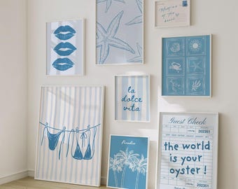 May include: Collection of framed art prints with a beach theme. Prints include blue lips, starfish, striped patterns, bikini, palm trees, and the phrases "la dolce vita" and "the world is your oyster!" in white frames.