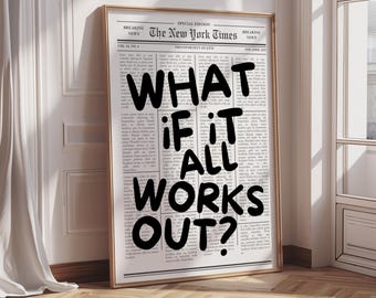 May include: A framed print featuring a newspaper-style design with the headline "WHAT IF IT ALL WORKS OUT?". The print has a gold frame and is leaning against a white wall and wooden floor.