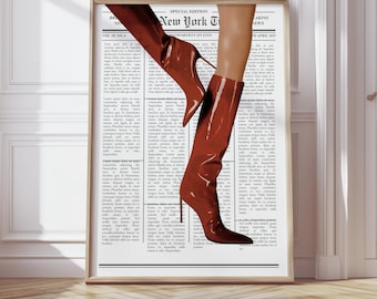May include: A framed print featuring a pair of glossy, knee-high, reddish-brown boots with stiletto heels. The boots are set against a backdrop of a newspaper page with the text "New York Ti" and "WORTHY ON ETSY". The print is displayed in a room with white walls.
