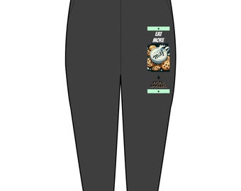 Può includere: Pantaloni della tuta grigio scuro con vita con coulisse. Una grafica rettangolare sulla gamba destra presenta una tazza di latte e biscotti con il testo "Eat More Milf" e "Filth Apparel".