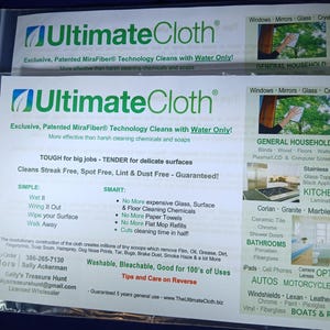 May include: A green and white Ultimate Cloth cleaning cloth with the text "Exclusive, Patented MiraFiber Technology Cleans with Water Only!" and "More effective than harsh cleaning chemicals and soaps". The cloth is advertised as being tough for big jobs and tender for delicate surfaces. It is also advertised as being streak free, spot free, lint and dust free. The cloth is washable, bleachable, and good for 100's of uses. The back of the cloth has a list of surfaces it can clean, including windows, mirrors, glass, crystal, general household, blinds, wood, floors, walls, plasma/LCD and computer screens, stainless steel, glass-topped and black appliances, kitchens, laminates, corian, granite, marble, ceramic tile, chrome, shower doors, bathrooms, porcelain, fiberglass, iPads, cell phones, camera lenses, optics, autos, motorcycles, windshields, lexan, leather, chrome, paint, plexiglas, vinyl, fiberglass, boats and RVs.