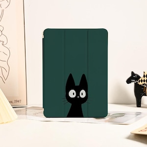 Op de afbeelding: Een groene iPad-hoes met een zwarte kat-illustratie. De kat heeft grote witte ogen en kijkt omhoog.