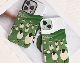 May include: Two phone cases with a whimsical design featuring a flock of sheep grazing on a green hillside under a white sky. The cases have a white top section and a green bottom section with the sheep illustration.