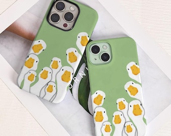 May include: Two green phone cases with a repeating pattern of white and yellow duck faces. The cases have a matte finish and are designed to fit a smartphone. The cases are on a white surface.