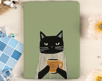 Puede incluir: Una funda rectangular para lector electrónico con fondo verde salvia que presenta una ilustración gráfica de un gato negro con un suéter de rayas blancas y negras, sosteniendo una taza amarilla con rayas horizontales marrones en sus patas.