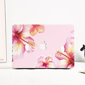May include: Pink laptop case featuring a floral design with watercolor hibiscus flowers in shades of pink, yellow, and red. The case has a cutout for the Apple logo.
