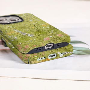 May include: Two green floral patterned phone cases stacked on top of each other. The cases feature a design of flowers and leaves in shades of green, yellow, and pink. The cases have black edges and openings for the camera and charging port.