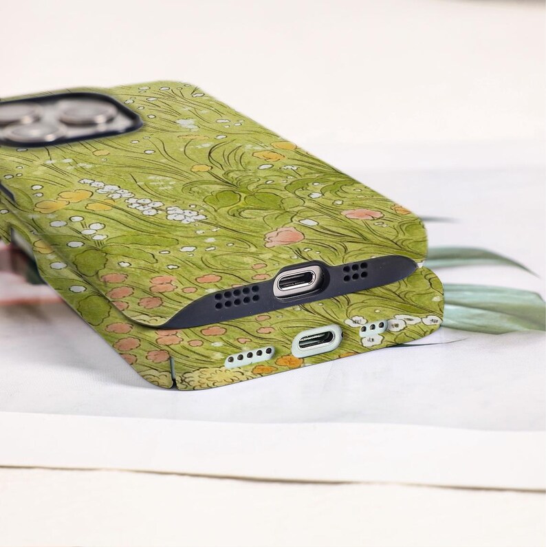 May include: Two green floral patterned phone cases stacked on top of each other. The cases feature a design of flowers and leaves in shades of green, yellow, and pink. The cases have black edges and openings for the camera and charging port.