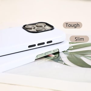 May include: Two white phone cases stacked on top of each other. The top case has a camera cutout with black trim and three black buttons. The bottom case has two green buttons. The words "Tough" and "Slim" are visible.