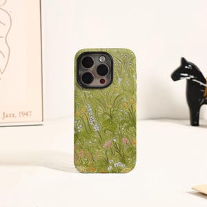 May include: A phone case featuring a floral design with a green background. The case has a pattern of yellow, white, and pink flowers and green foliage. The phone case has a camera cutout and a black border.