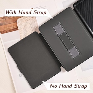 May include: A black e-reader case shown in two configurations: one side features a gray elastic hand strap for secure holding, while the other side is a plain black interior surface. The text "With Hand Strap" and "No Hand Strap" is visible.
