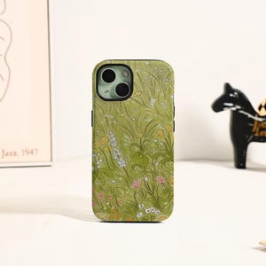 May include: A phone case with a floral design. The case features a green background with a pattern of wildflowers in shades of white, yellow, and pink. The phone case is designed to fit a smartphone.