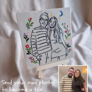 May include: A square ceramic tile with a black and white line drawing of a couple, framed by floral designs. The tile is presented on a miniature wooden easel. The text "Send your own photo to become a tile!" is visible.