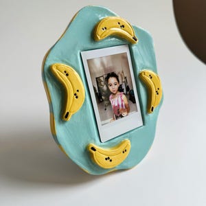 Handmade Ceramic Polaroid Holder – Wavy Blue Frame with Cute Banana Accents – Whimsical Fruit-Themed Photo Display