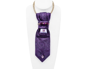 Collana con cravatta a fantasia paisley viola, catena dorata e dettagli in pietre preziose.