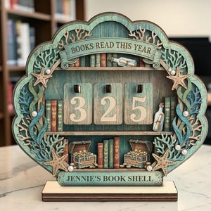 May include: A wooden bookshelf-shaped counter with the text "BOOKS READ THIS YEAR" and the numbers "325". The shelf is decorated with starfish, coral, and treasure chests. The text "JENNIE'S BOOK SHELL" is at the bottom.