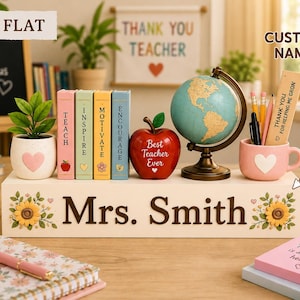 May include: A white wooden desk organizer featuring the name Mrs. Smith in brown text, decorated with sunflowers. It holds a small potted plant, four miniature books labeled Teach, Inspire, Motivate, Encourage, a red apple, a globe, and a mug with pens.