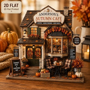 May include: A miniature 2D flat printed model of Anderson's Autumn Cafe. The structure features a brown roof, dark green doors with wreaths, a bay window, and a sign reading Coffee, Good Friends, Cozy Days. It is decorated with pumpkins and fall foliage.