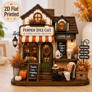 Op de afbeelding: Een decoratief miniatuur Pumpkin Spice Café met een gestreepte luifel, een koffiebar en herfstdecoratie. Het gebouw toont borden met de tekst Pumpkin Spice Café, Coffee Bar en Pumpkin Spice Everything Nice.