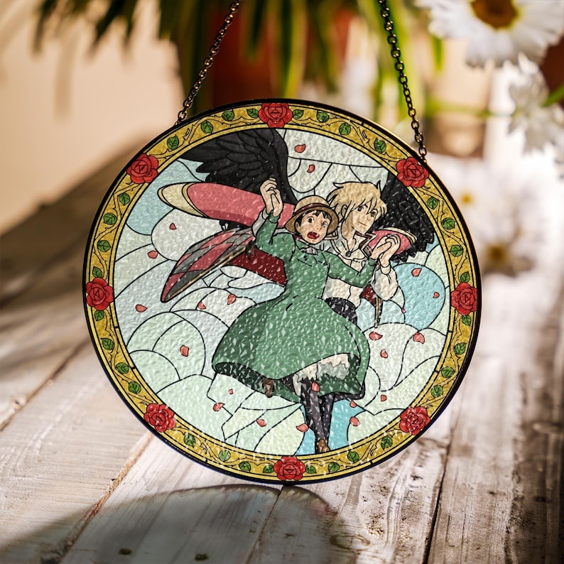 May include: Round stained glass window featuring a colorful anime scene with two characters. The design includes a green dress, wings, and a floral border with red roses. The window is hanging by a chain.