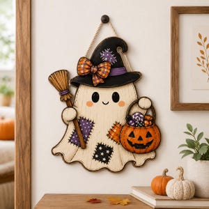 May include: A wall hanging decoration shaped like a ghost wearing a black witch hat with a plaid bow. The ghost features purple and orange patches, holds a wooden broom, and carries an orange jack-o'-lantern bucket filled with colorful candy.